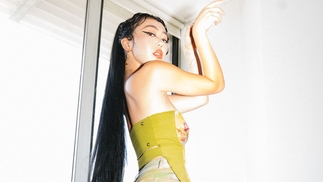 Photo of Elle Shimada posing against a wall wearing a neon green bodice